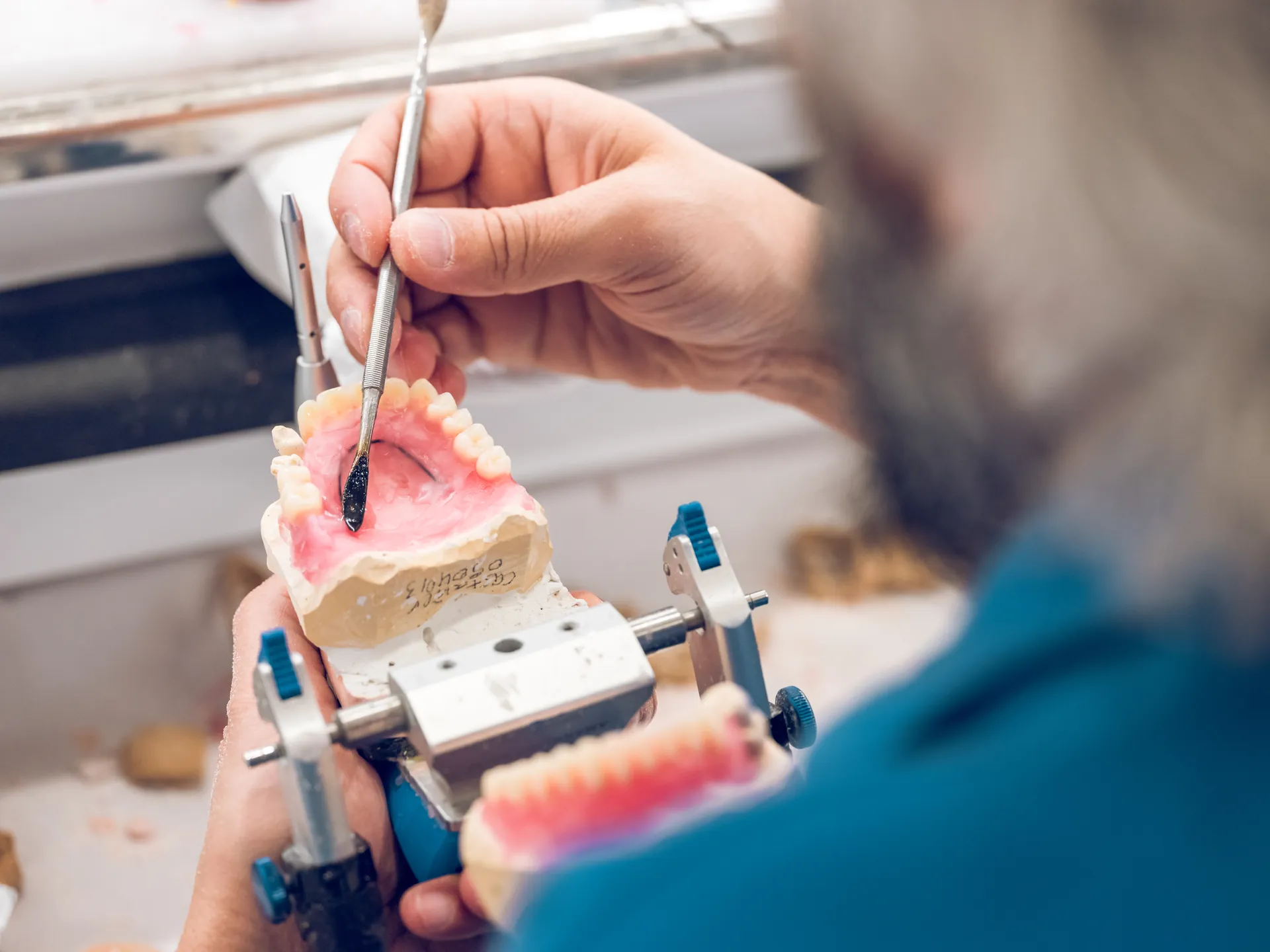 Tandtechnicus werkt aan een prothese in de articulator