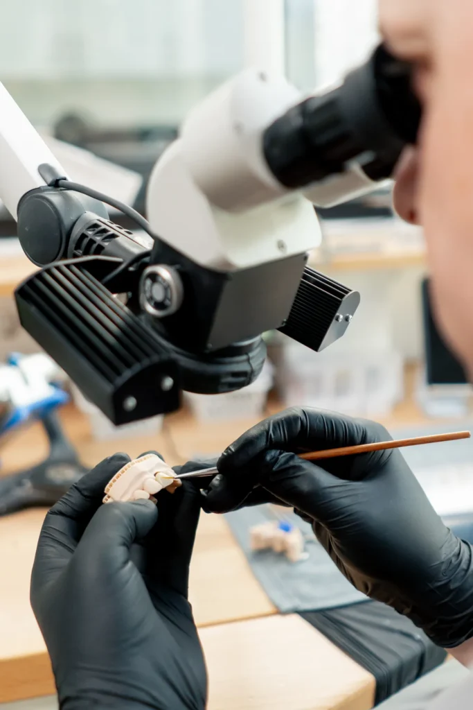 Tandtechnicus werkt onder de microscoop aan een tandmodel